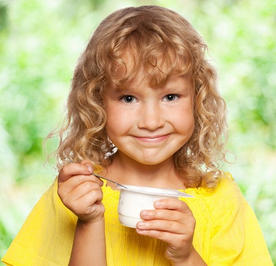 Fetita ce tine in mana un borcanel de iaurt
