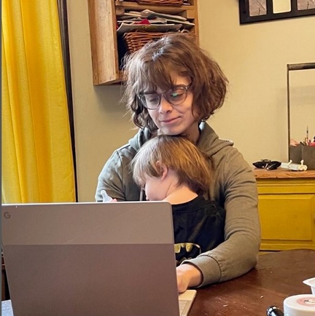 mama-care-lucreaza-pe-laptop-in-timp-ce-isi-tine-in-brate-copilul