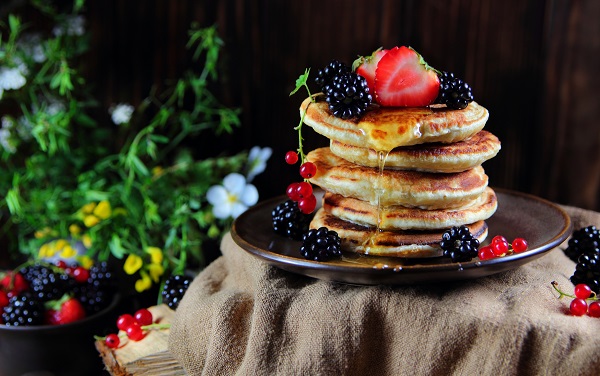 clatite tip pancakes puse pe o farfurie, decorate cu diverse fructe de padure