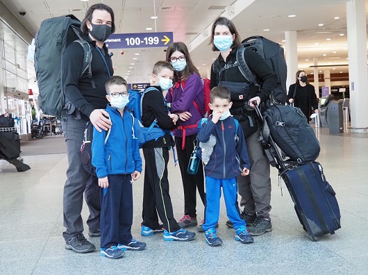 parinti si cei patru copii ai lor purtand masti de protectie in timp ce se afla intr-un aeroport