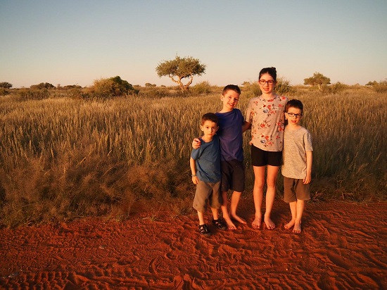 patru frati, trei baieti si o fata, impreuna intr-un peisaj de savana din Africa