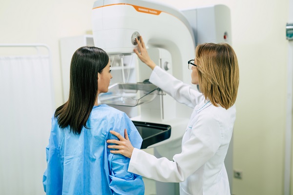 cadru medical care pregateste o pacienta tanara pentru o mamografie