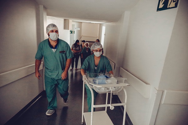 cadre medicale pe holurile unui spital, transportand un patut cu un nou-nascut
