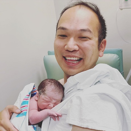 barbat de origine asiatica fericit tinandu-si nou-nascutul la piept