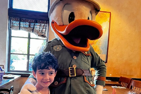baietel pozandu-se cu personajul Donald Duck