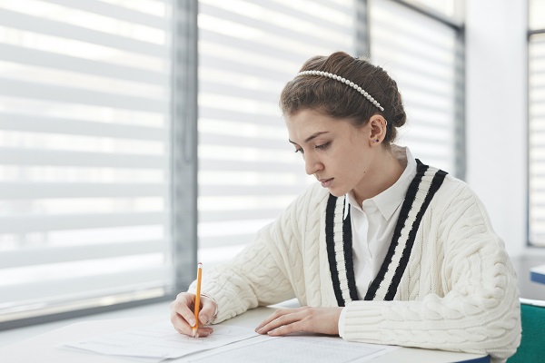eleva in pulover alb cu negru scriind in timpul unui examen