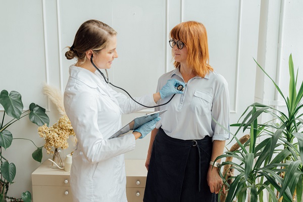 doctorita zambitoare care o asculta cu stetoscopul o femeie in fusta neagra