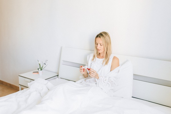 femeie care sta in pat si se uita la rezultatul unui test de sarcina