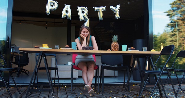 femeie tanara stand trista si singura la petrecerea ei aniversara