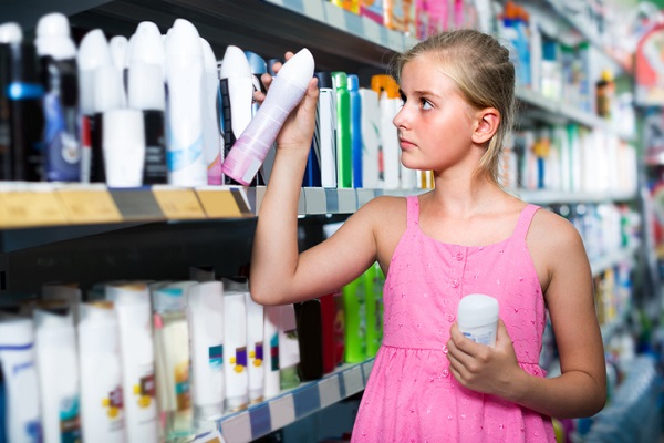 adolescenta in rochita roz in magazin incercand sa aleaga un deodorant de la raft
