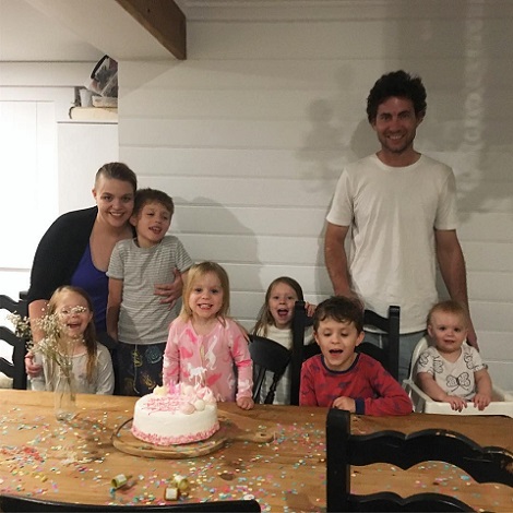 parinti fericiti cu cei sase copii ai lor stand la masa cu ocazia aniversarii unuia dintre ei