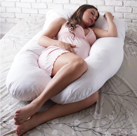 femeie tanara insarcinata dormind pe o perna pentru gravide alba