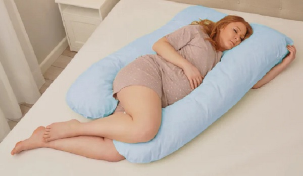 femeie insarcinata dormind pe o perna pentru gravide bleu