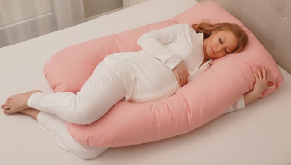 femeie insarcinata care doarme pe o perna pentru gravide roz