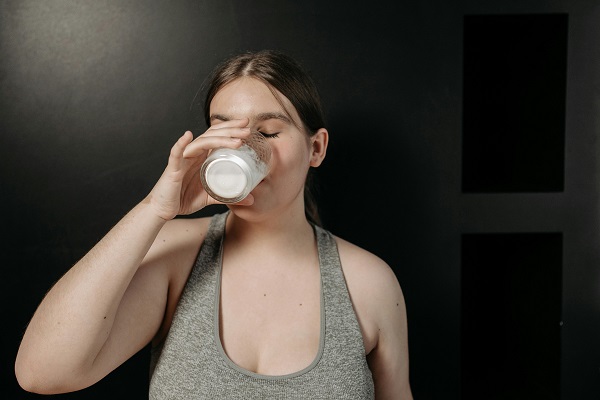 femeie tanara purtand top decoltat si band lapte din pahar