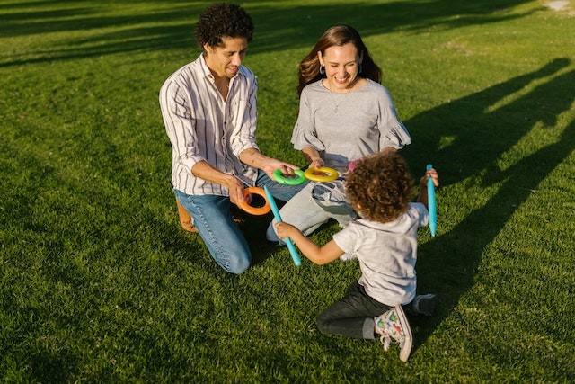 parintii si copilul se joaca pe iarba