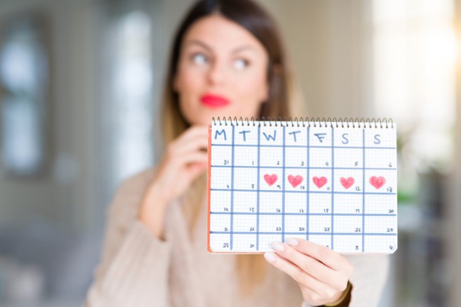 femeie care tine in mana un calendar menstrual