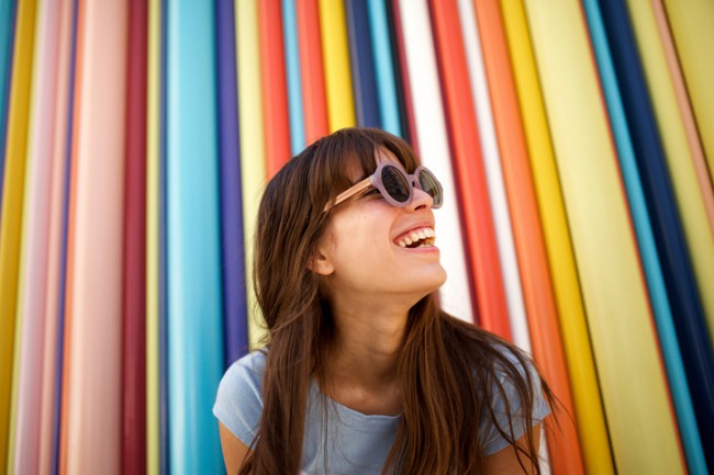 femeie cu ochelari de soare care sta in fata unui zid colorat