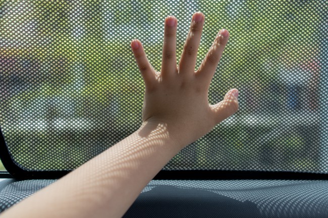 copil care tine mana pe geamul unei masini
