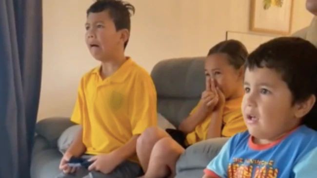 trei copii care se uita la televizor