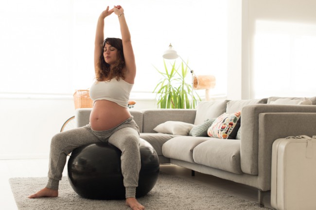 Femeie gravidă care face exerciții de relaxare cu un fitball