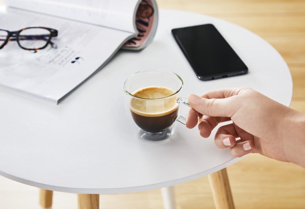 ceasca de cafea pe masa langa telefon