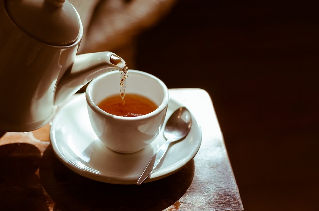 ceasca de ceai alba care este umpluta cu ceai dintr-un ceainic alb