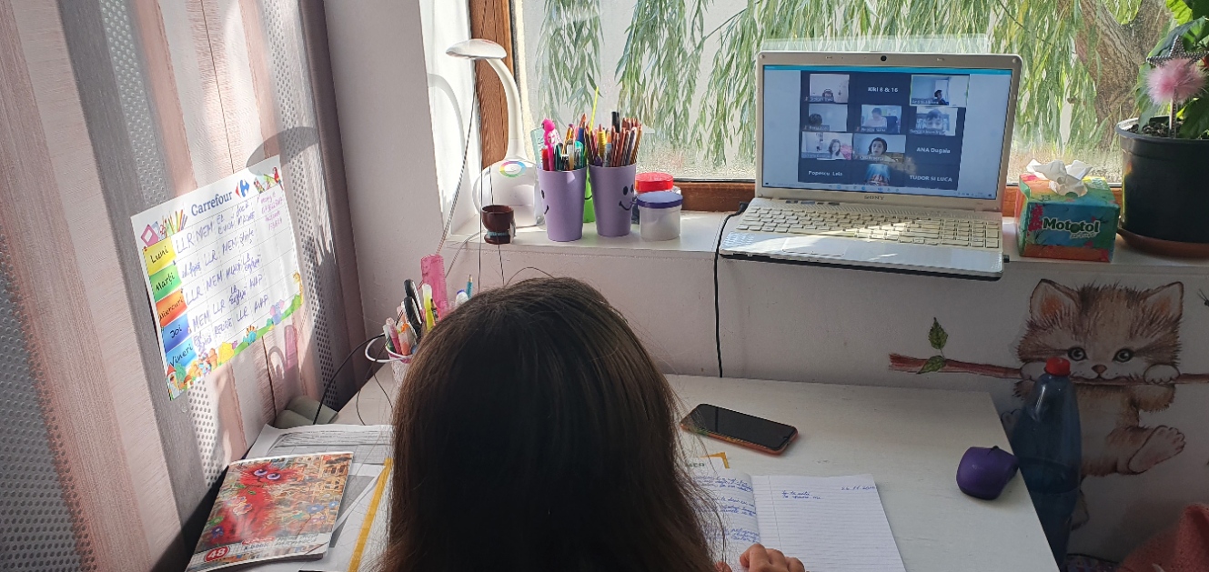 copil care face scoala online asezat la birou