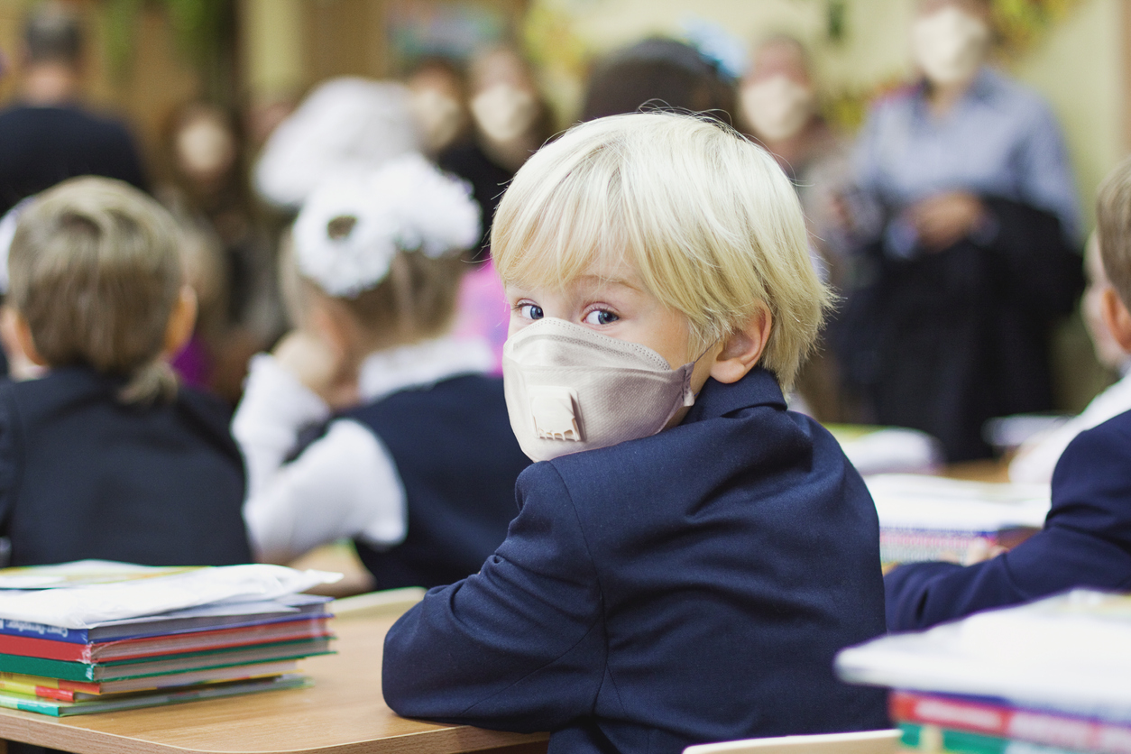copil blond in banca la scoala purtand masca
