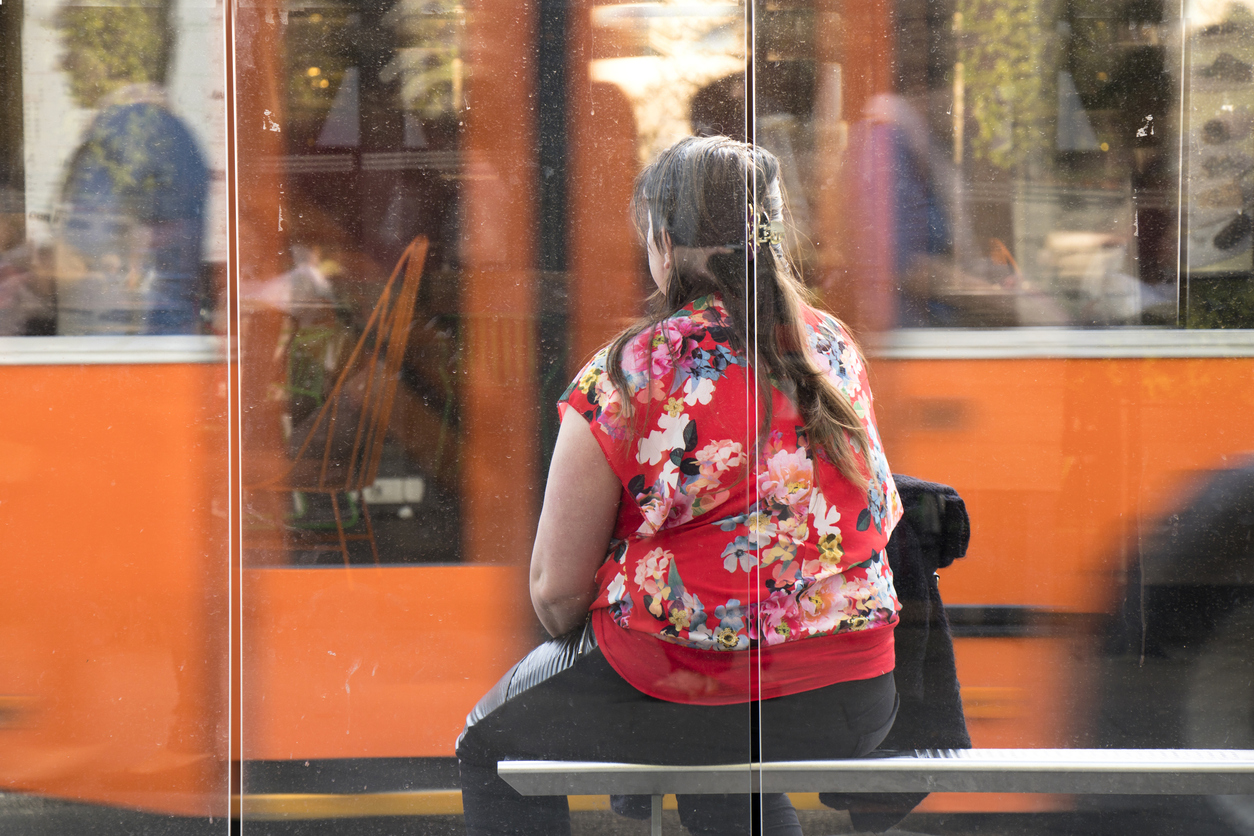 femeie obeza care asteapta autobuzul in statie