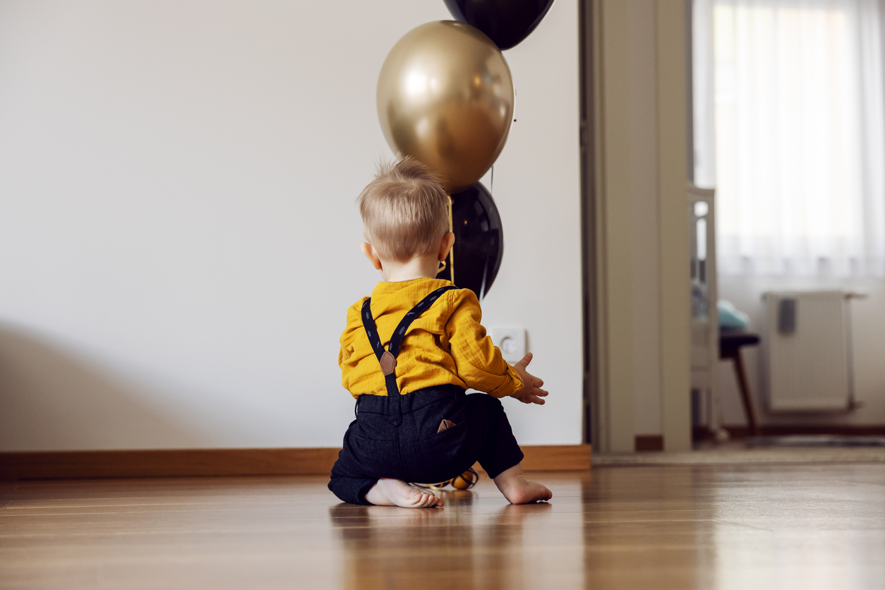 copil mic care se joaca in casa cu baloane