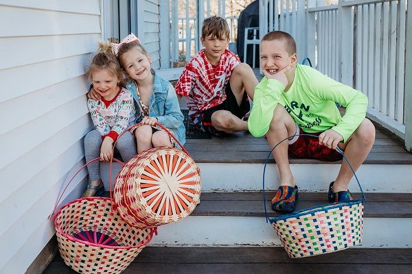 patru copii pe veranda cu cosuri in mana