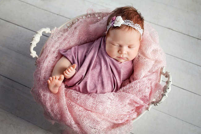 bebelus-fetita-care-doarme-si-sta-intr-un-cos-si-este-imbracata-in-roz