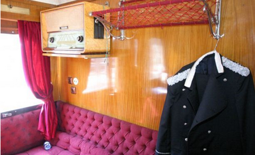 trenul-regal-un-vagon-care-are-canapea-si-perdea-rosie-o-haina-neagra-cu-alb-si-un-radio-vechi