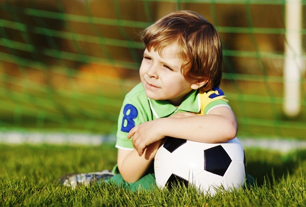 poza copil cu mingea pe terenul de fotbal