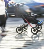 Copil plimbat în cărucior pe lângă o mașină aflată în mers!