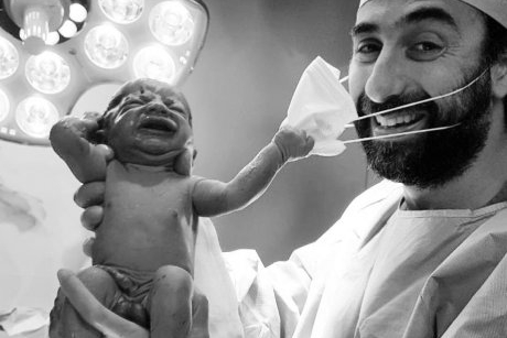 Fotografia care dă speranță umanității: nou-născutul care trage de masca medicului care l-a adus pe lume