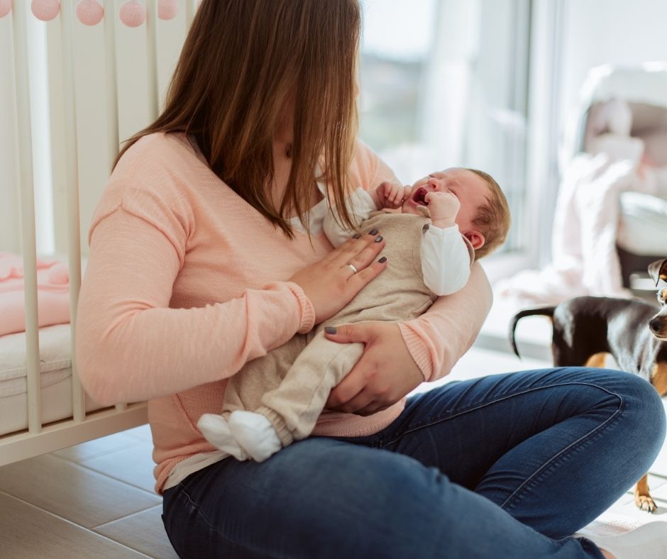 mama care isi tine bebelusul in brate si se uita la el cu dragoste