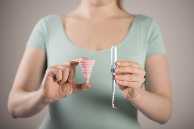 femeie care tine in mana o cupa menstruala si un tampon