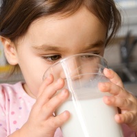 Copil care bea lapte din pahar