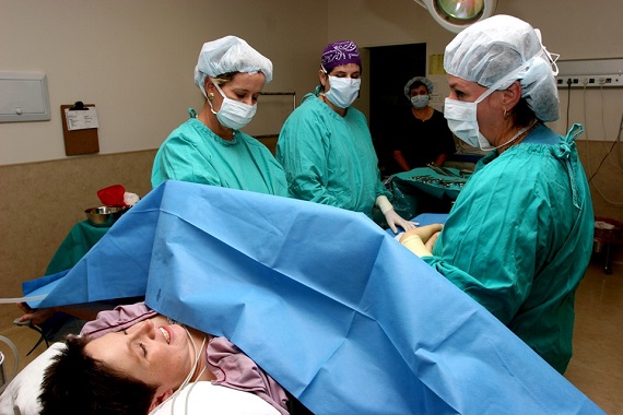 Femeie aflata in sala de operatie, alaturi de personalul medical