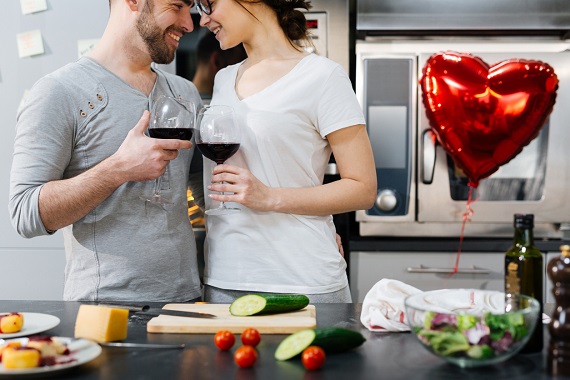 Cuplu in bucatarie, ciocnind cate un pahar de vin