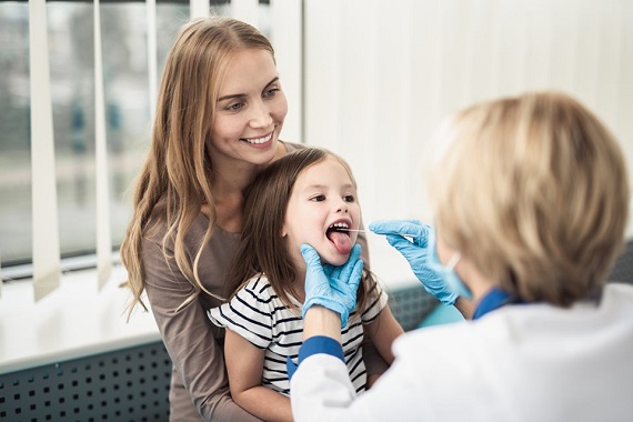 Mama cu copilul ei la medic, pentru ca acesta sa ii examineze in gat