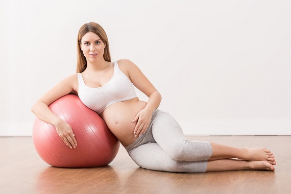 Femeie insarcinata cu o minge de gimnastica