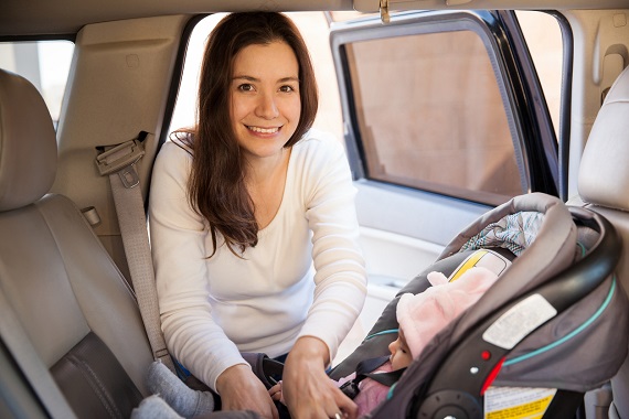 Mama care isi verifica bebelusul pus in scaunul auto