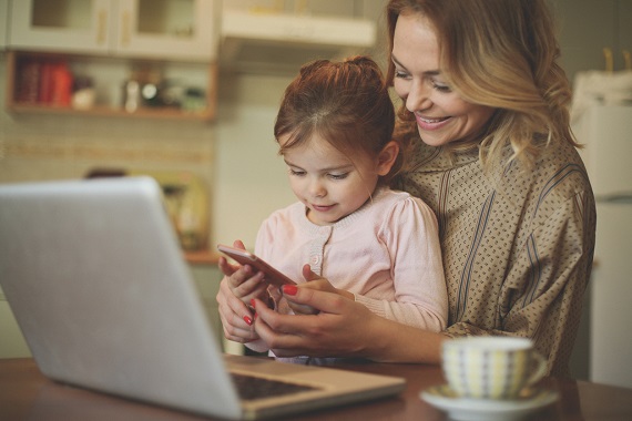 Mama alaturi de fiica ei, ce sta sa se joace pe telefon