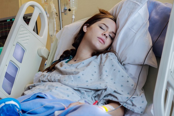 Femeie  aflata pe patul de spital, cu perfuzii