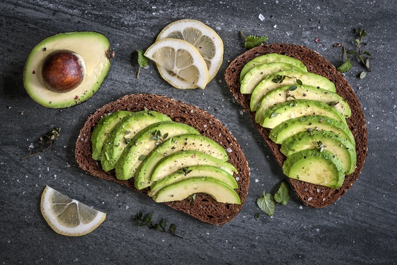 Sandvis cu avocado, pe paine graham, alaturi de avocado si felii de lamaie