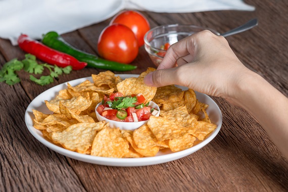 Femeie ce gusta din sos salsa cu nachos