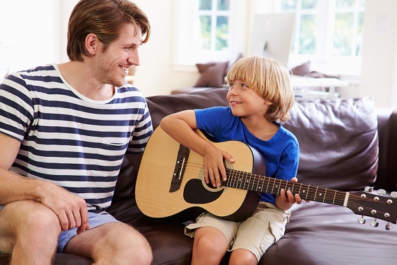 Tata ce este alaturi de fiul sau, care canta la chitara